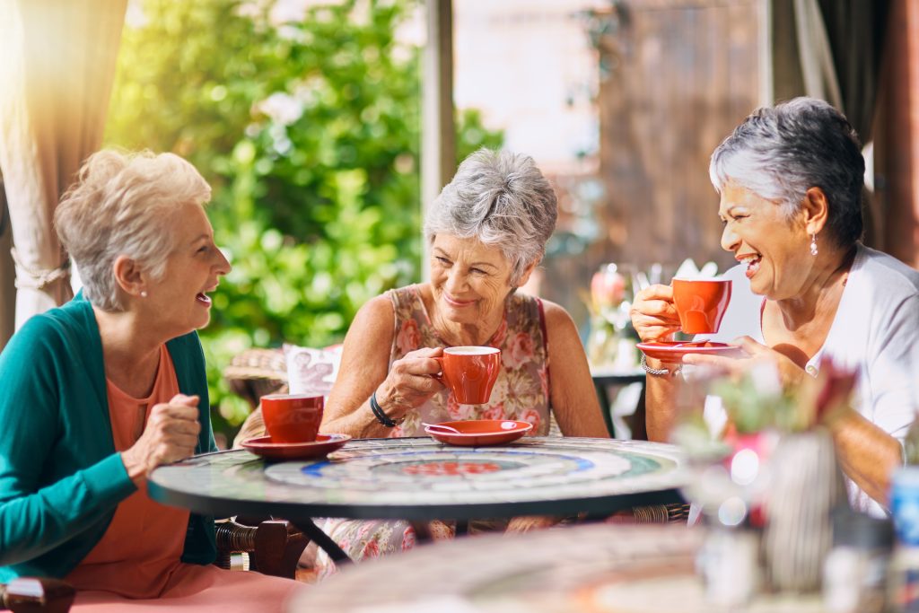 three women around a table laughing and drinking tea