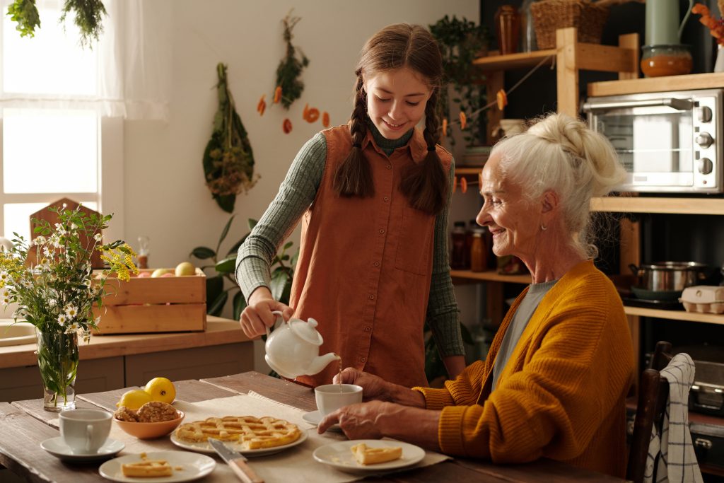 girl pouring tea for an older woman sitting at the kitchen table
